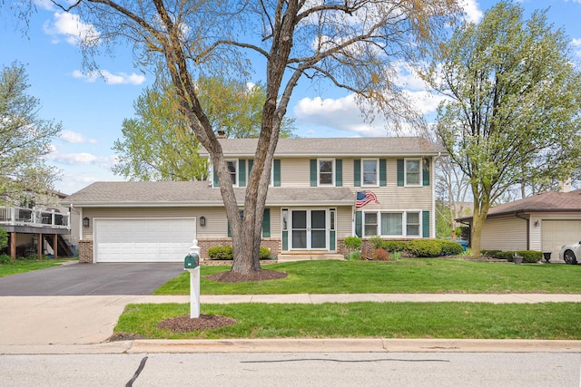 view of front of home featuring an attached garage, driveway, brick siding, and a front yard
