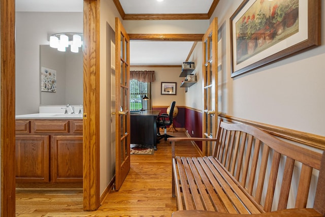 hallway with a sink, ornamental molding, french doors, and light wood finished floors