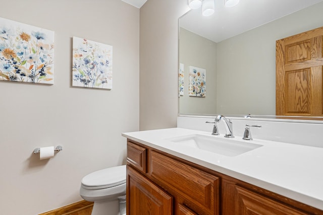 half bath featuring toilet, wood finished floors, and vanity