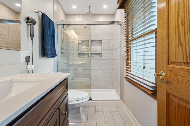 bathroom featuring vanity, recessed lighting, a stall shower, and toilet