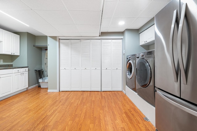 washroom with cabinet space, baseboards, recessed lighting, light wood-style flooring, and washer and clothes dryer