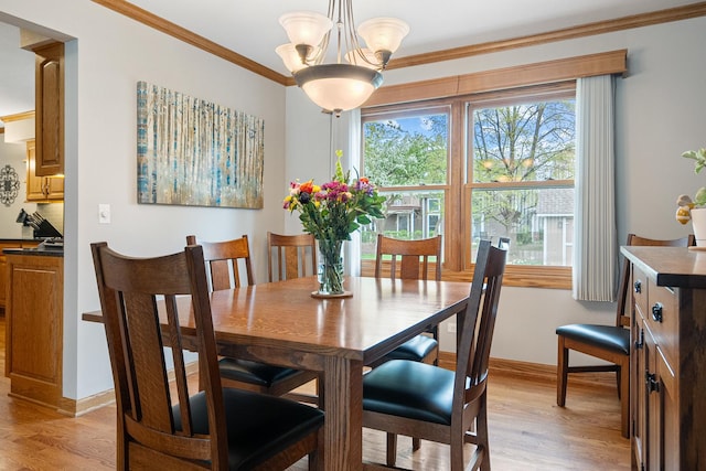 dining room featuring crown molding, baseboards, an inviting chandelier, and light wood finished floors