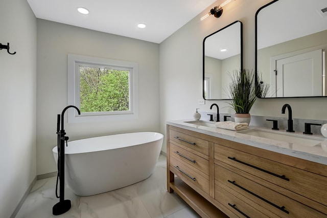 bathroom featuring double vanity, a sink, marble finish floor, and a freestanding bath