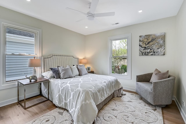 bedroom with baseboards, recessed lighting, wood finished floors, and visible vents