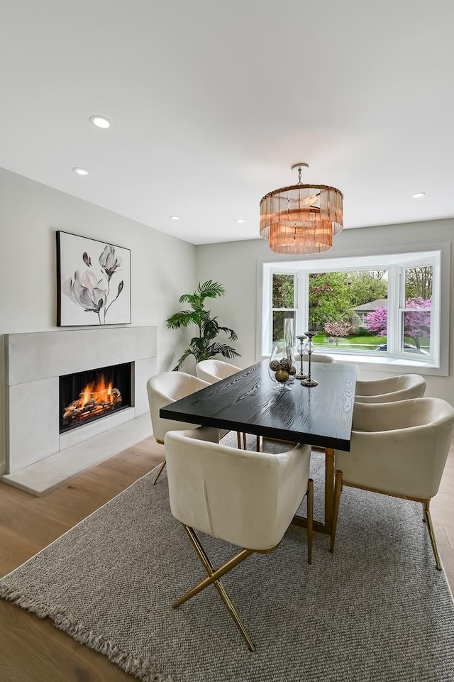 dining area with recessed lighting, wood finished floors, and a warm lit fireplace
