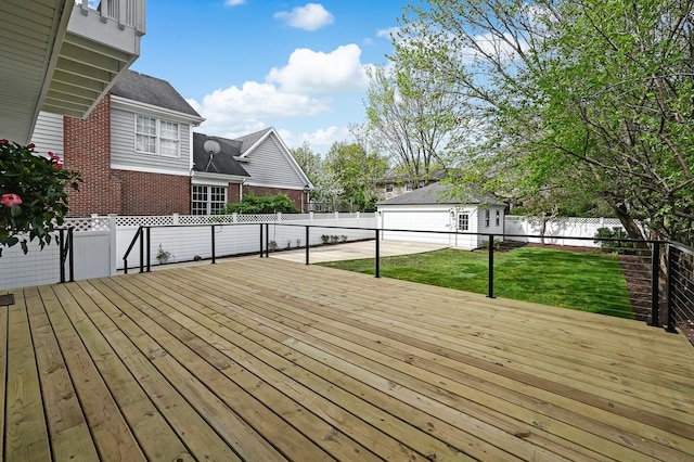 wooden terrace featuring a fenced backyard, an outdoor structure, and a yard