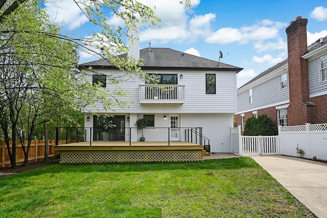 back of house featuring a lawn, a wooden deck, a fenced backyard, and a balcony