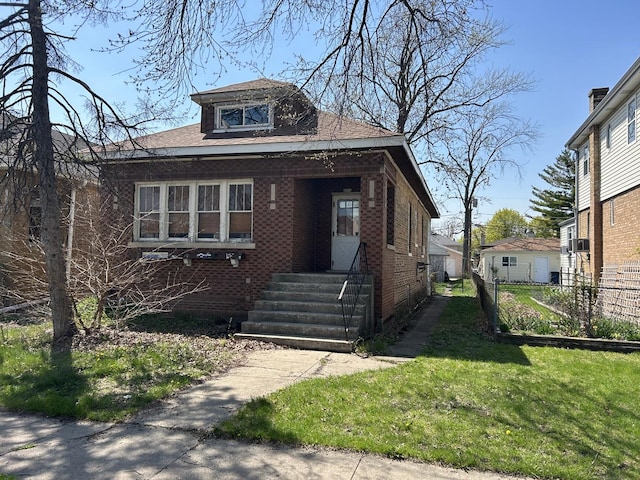 bungalow with brick siding and a front lawn