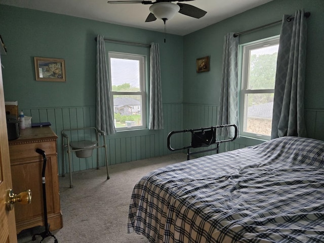 bedroom featuring ceiling fan, carpet, and a wainscoted wall