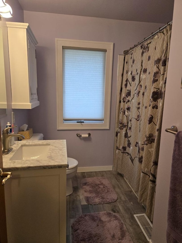 bathroom with visible vents, wood finished floors, vanity, baseboards, and toilet
