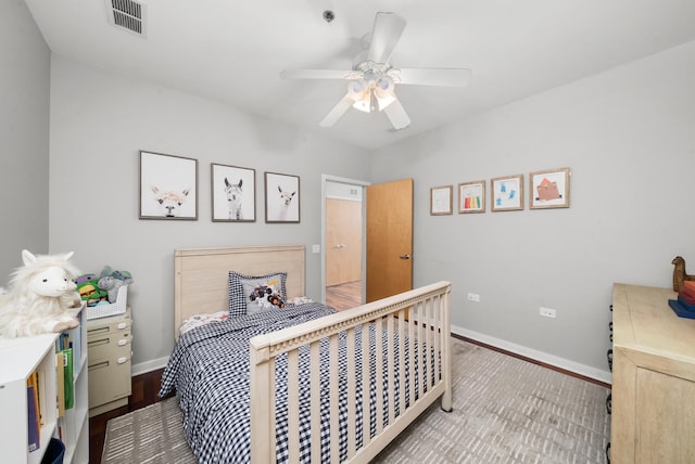 bedroom with baseboards, ceiling fan, visible vents, and wood finished floors