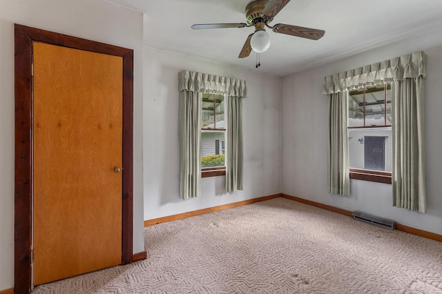 carpeted empty room with baseboards, ceiling fan, and visible vents