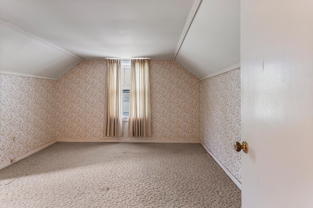 additional living space featuring baseboards, wallpapered walls, vaulted ceiling, and carpet flooring