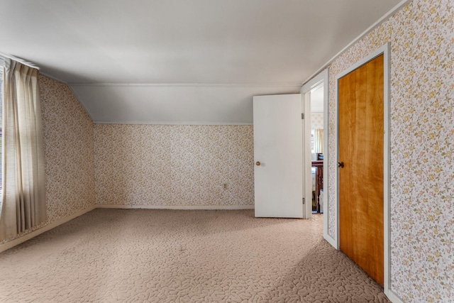 additional living space with carpet floors, vaulted ceiling, and wallpapered walls