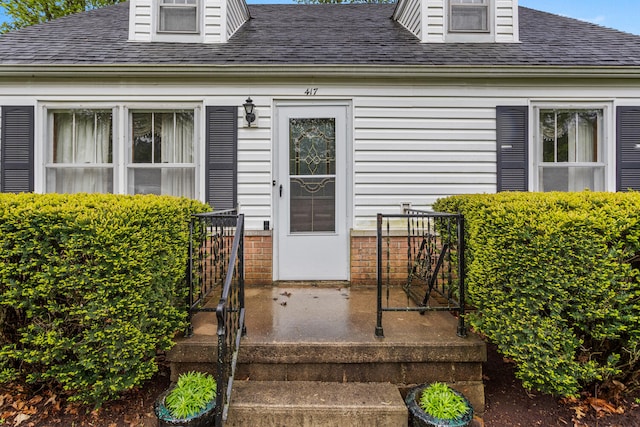 doorway to property with a shingled roof