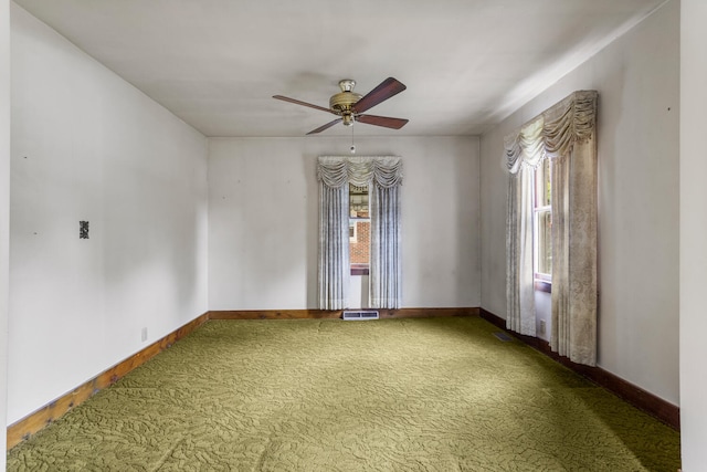 carpeted empty room featuring visible vents, a ceiling fan, baseboards, and a healthy amount of sunlight