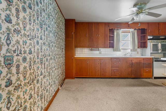 kitchen featuring brown cabinetry, open shelves, a sink, light countertops, and wallpapered walls