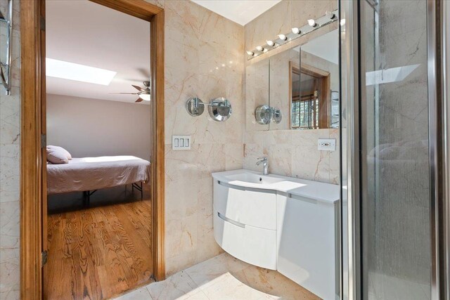 33 Half Day Rd, Lincolnshire, IL 60069 - ensuite bathroom with tile walls, a skylight, ceiling fan, vanity, and marble finish floors