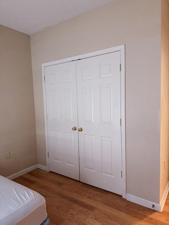 bedroom featuring baseboards, a closet, and wood finished floors