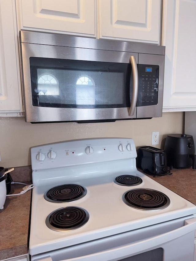room details with white range with electric cooktop, white cabinets, and stainless steel microwave