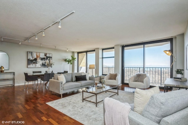 living room featuring track lighting, wood finished floors, baseboards, a textured ceiling, and a water view