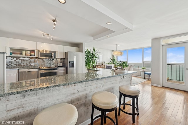 5733 N Sheridan Rd Unit 29D, Chicago, IL 60660 - kitchen with stainless steel appliances, white cabinets, a kitchen bar, tasteful backsplash, and dark stone counters
