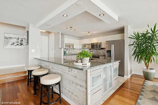 5733 N Sheridan Rd Unit 29D, Chicago, IL 60660 - kitchen featuring appliances with stainless steel finishes, light wood-type flooring, white cabinets, a breakfast bar, and baseboards