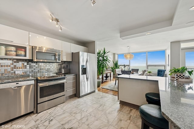 5733 N Sheridan Rd Unit 29D, Chicago, IL 60660 - kitchen with appliances with stainless steel finishes, white cabinets, tasteful backsplash, light marble finish flooring, and decorative light fixtures