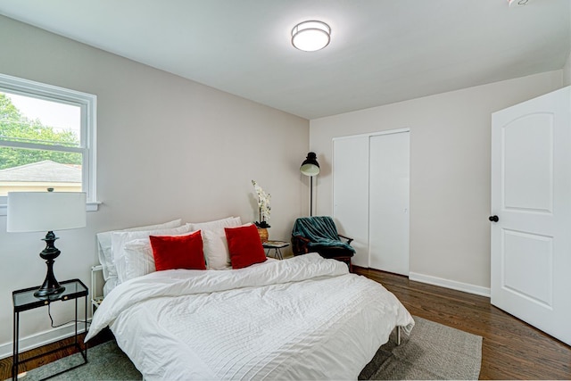 bedroom featuring baseboards, wood finished floors, and a closet