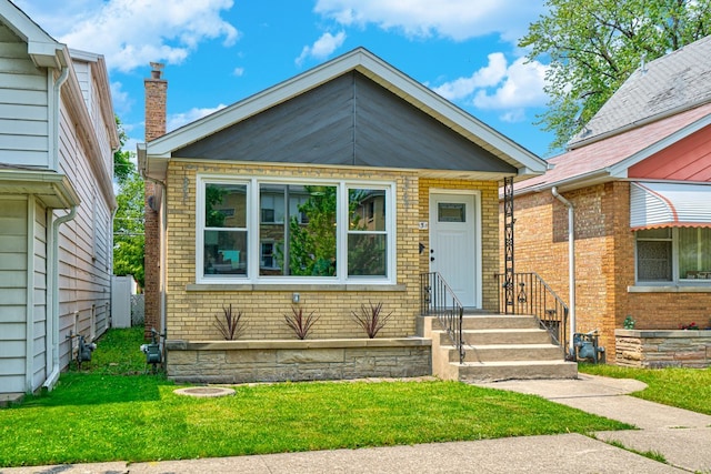 bungalow with brick siding and a front lawn