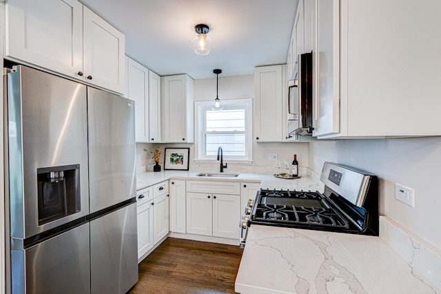 kitchen with dark wood-style flooring, appliances with stainless steel finishes, light stone counters, a sink, and white cabinetry