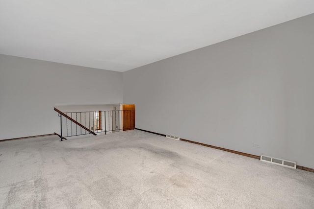 unfurnished room featuring light colored carpet, visible vents, and baseboards