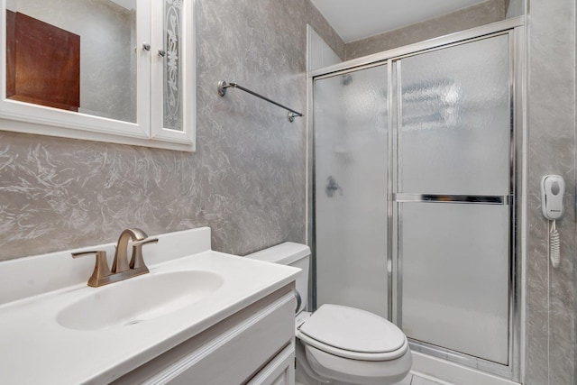 full bathroom with wallpapered walls, toilet, a shower stall, and vanity
