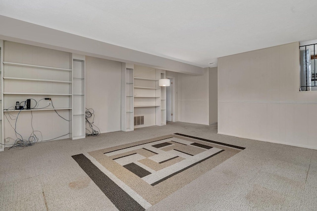 finished below grade area with carpet, visible vents, and built in shelves