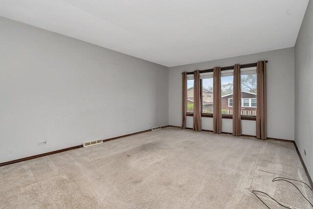 empty room with visible vents, baseboards, and light carpet