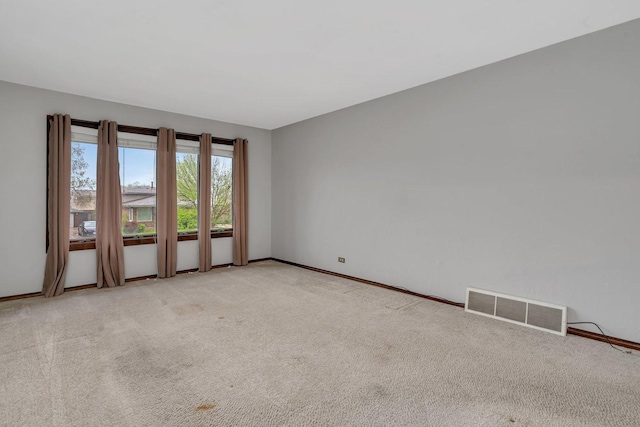 empty room with light colored carpet, baseboards, and visible vents