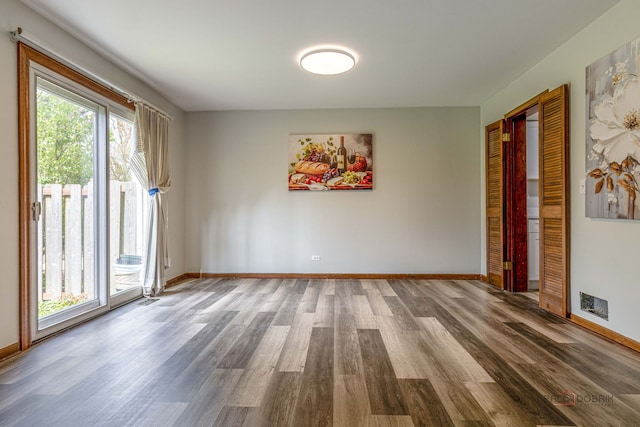 unfurnished room featuring visible vents, baseboards, and wood finished floors