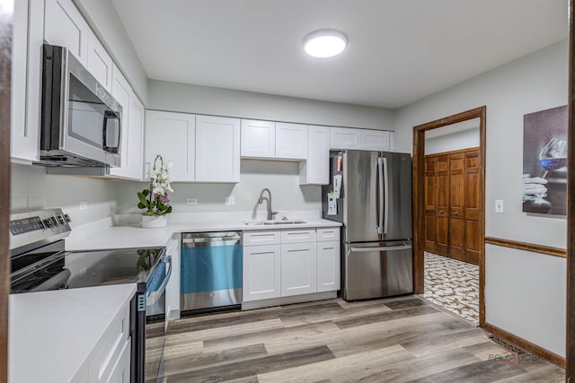 kitchen featuring light wood-style floors, a sink, appliances with stainless steel finishes, and white cabinets