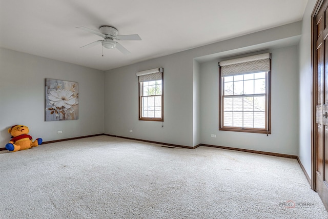 interior space with visible vents, baseboards, ceiling fan, and light colored carpet