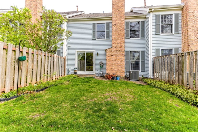 back of property featuring a fenced backyard, central AC unit, a chimney, and a yard