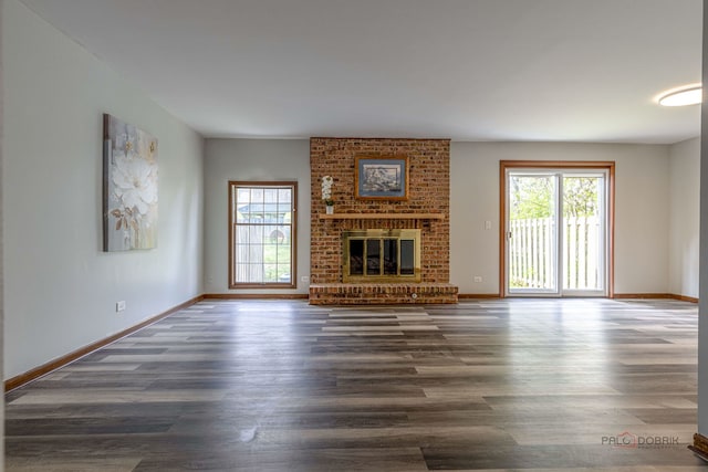 unfurnished living room featuring plenty of natural light, wood finished floors, and a fireplace