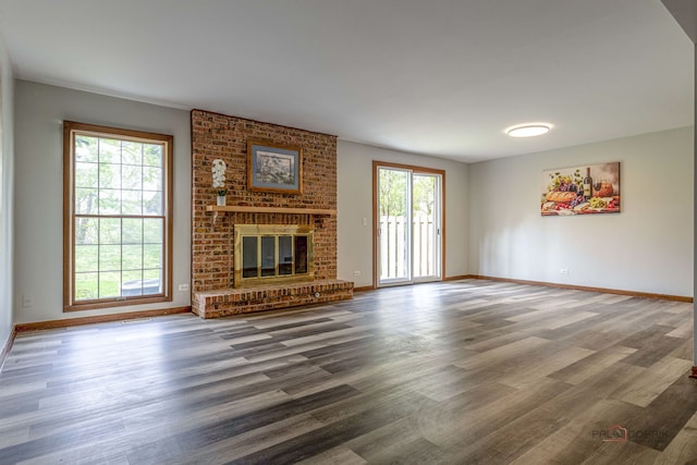 unfurnished living room featuring baseboards, a brick fireplace, and wood finished floors