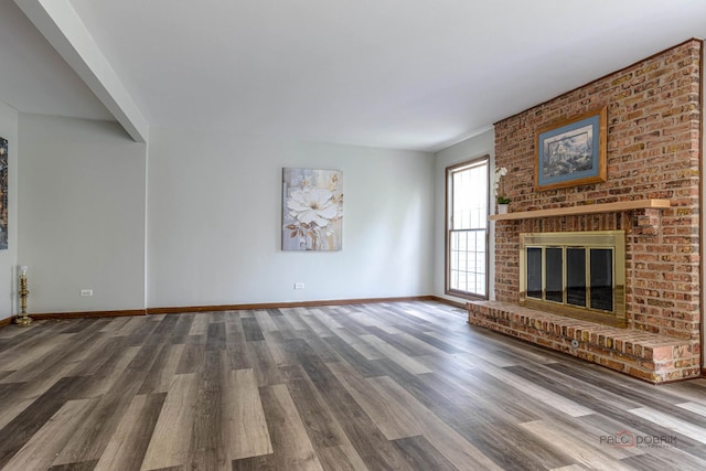 unfurnished living room with a brick fireplace, baseboards, and wood finished floors