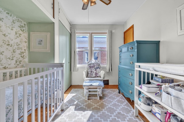 bedroom featuring wallpapered walls, a closet, wood finished floors, and a ceiling fan