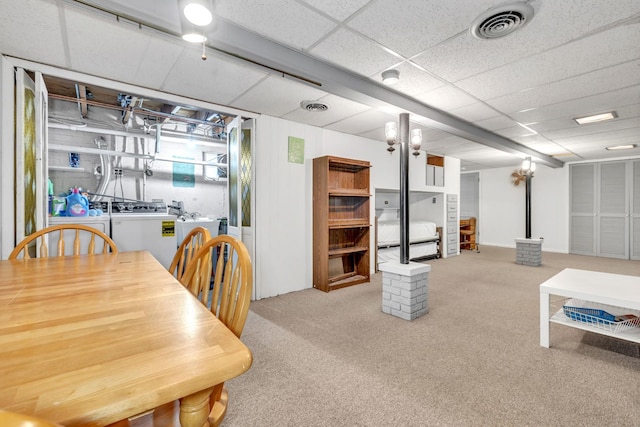 dining room featuring carpet flooring, washer and clothes dryer, and a drop ceiling