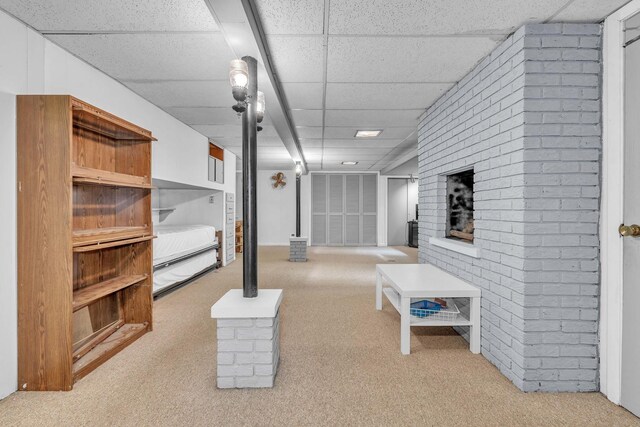 finished below grade area with a drop ceiling, carpet floors, and brick wall