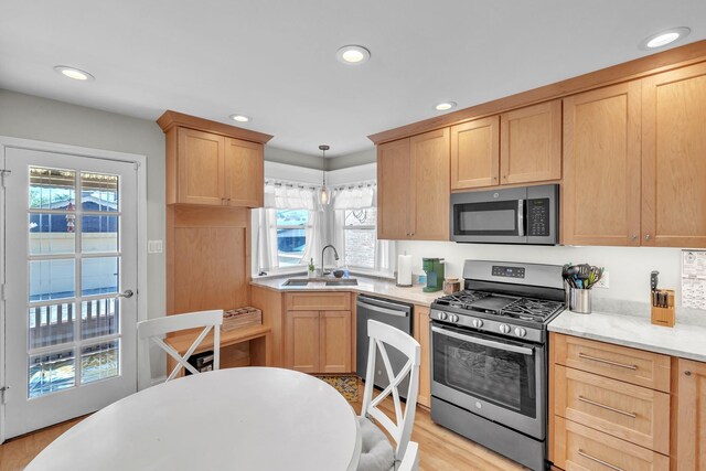 kitchen with appliances with stainless steel finishes, a sink, light brown cabinetry, recessed lighting, and light wood-style flooring