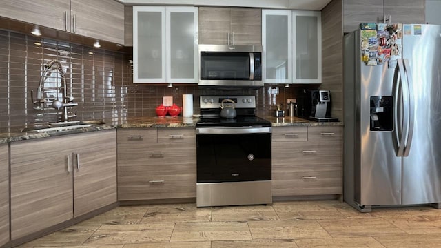 kitchen featuring stone counters, decorative backsplash, and stainless steel appliances