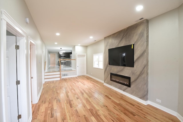 unfurnished living room with light wood-style floors, a large fireplace, baseboards, and recessed lighting