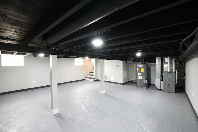below grade area featuring baseboards, heating unit, stairway, and electric water heater